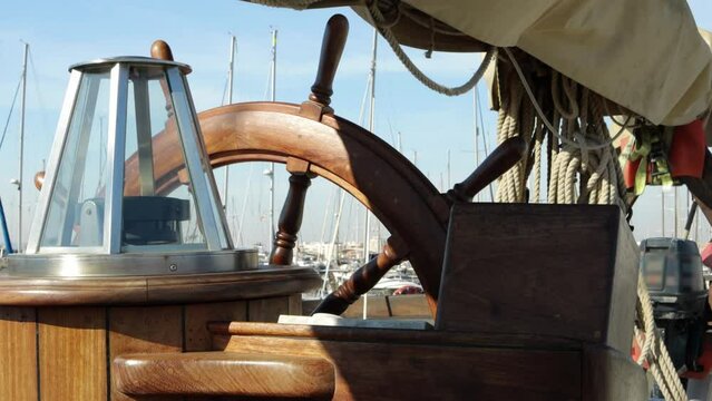 Close-up of the steering wheel and deck of a wooden antique sailboat. Steering wheel with compass