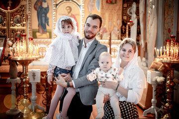a family with children in an Orthodox Christian church or temple are praying or have come to the sacrament of baptism, believers in a holy place, introducing children to the faith