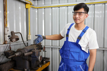 factory worker or technician showing lathe machine in factory