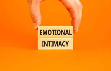 Emotional intimacy symbol. Concept words Emotional intimacy on beautiful wooden blocks. Beautiful orange table orange background. Psychologist hand. Psychology emotional intimacy concept. Copy space.