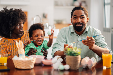 Fototapeta na wymiar Cheerful african american family is painting easter eggs together.