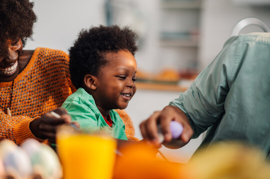 African american family having fun while decorating easter eggs at home