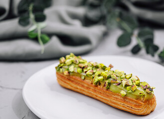 Sweet eclairs with dry pistachios on plate
