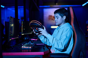 young woman putting headphones on table after playing game in a blue lit room, cybersport © LIGHTFIELD STUDIOS