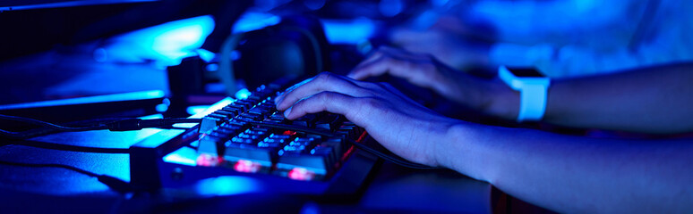 cropped banner of female hands, young gamer using computer keyboard while playing game, cybersport - obrazy, fototapety, plakaty