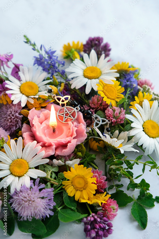 Canvas Prints flower shape candle with wiccan pentacle amulet and colorful flowers on table close up. esoteric rit