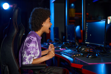 Fototapeta na wymiar excited african american player screaming from joy while winning computer game, cybersport