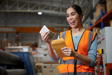factory worker smiling and counting money from envelope in the warehouse storage