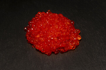 Red trout caviar on a black background.