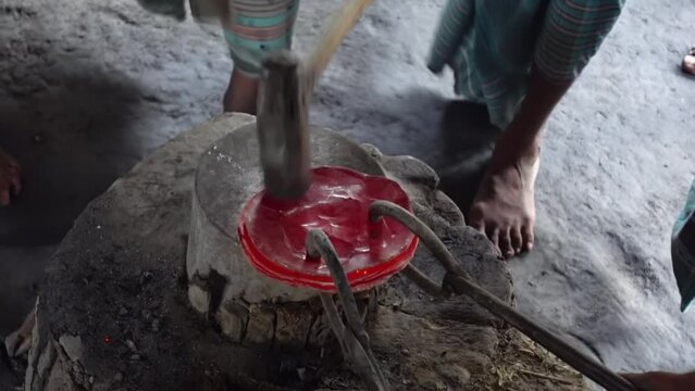 Hot bronze sheets are beaten with large hammers to make household appliances.