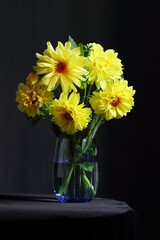 Bouquet of beautiful yellow flowers in a vase on dark moody black background, colorful composition for celebtarion design and concept, vertical