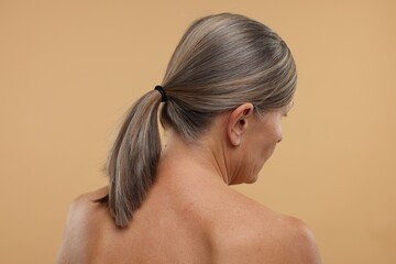 Fototapeta premium Mature woman with healthy skin on beige background, back view