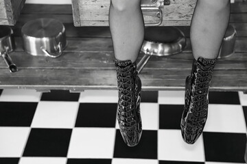 Fetisch Model mit schwarzen Hochglanz Lack Ballet Boots / Ballet Heels und Nylons mit Naht sitzt in der Küche - obrazy, fototapety, plakaty