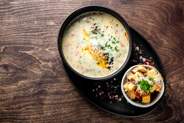 Salmon soup with cream, potatoes, carrots and parsley on wooden background
