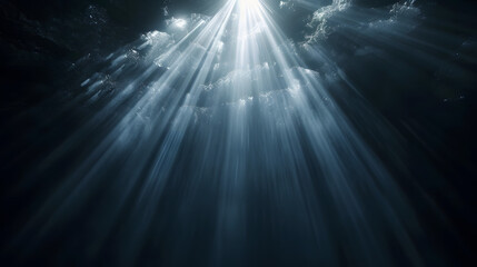 Sun rays and light shining through surface of ocean seen from underwater on black background