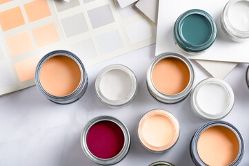 Tiny sample paint cans during house renovation, process of choosing paint for the walls, Peach Fuzz color of the year 2024, color charts on background