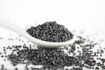 Spoon with poppy seeds on white background