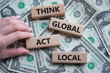 Think global act local symbol. Wooden blocks with words Think global act local. Beautiful dollar background. Businessman hand. Business and Think global act local concept. Copy space. - obrazy, fototapety, plakaty