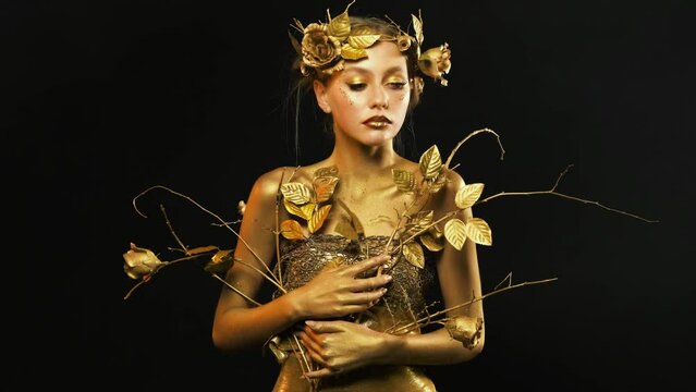 Art Portrait Closeup goddess of nature Beauty woman fashion model posing at studio Golden shiny skin red lips cat eyes looking at camera. blonde girl sexy body in gold paint metallic makeup fairy elf