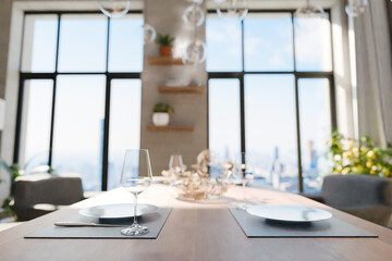 closeup of dining table in luxurious loft apartment with floor-to-ceiling windows and panoramic view; modern minimalistic interior design; bright daylight; 3D rendering