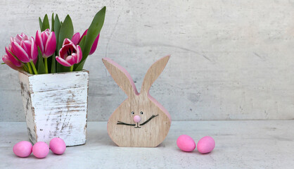 Osterdekoration mit Blumenstrauß, Ostereiern und einem lustigen Osterhasen mit Platz für Text.