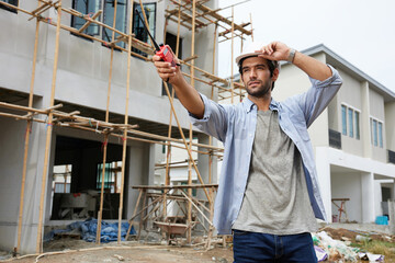 worker or architect using walkie talkie and talking to someone at construction site