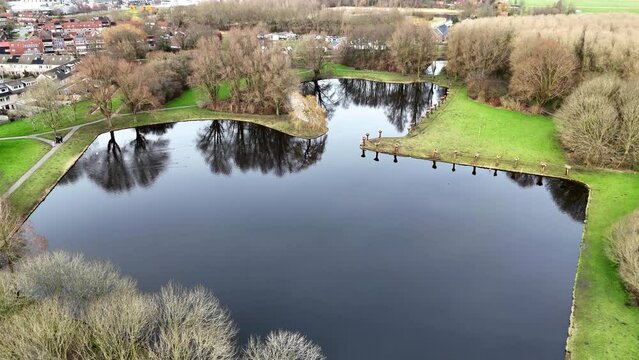 a pond in a park in Hellevoetsluis with pollarded willows in the foreground drone made movie