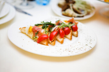 Fototapeta na wymiar Plate of delicious toast with tomatoes and herbs