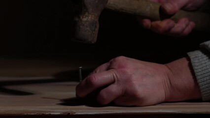 Hand hitting a nail into wood