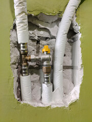 Metal plastic plumbing pipes with fitting and faucet in broken cement wall. Plumbing repair and replacement