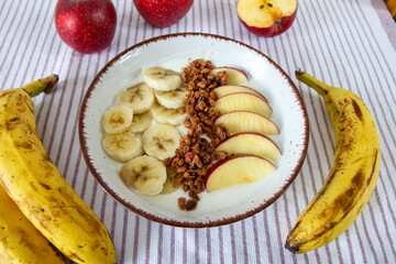 Zdrowe śniadanie z jogurtem naturalnym, granolą, jabłkiem i bananami