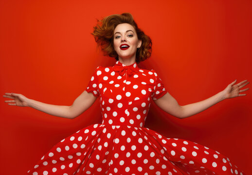 A woman stands confidently wearing a red and white polka dot dress.
