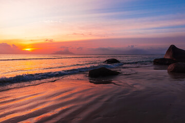 Fototapeta na wymiar Seaside landscape with wet sand and coastal stones on the sunset