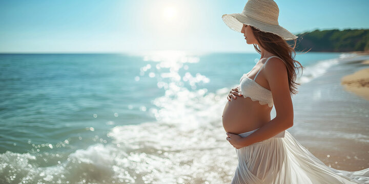A young pregnant woman in a white swimsuit and a hat walks along the seashore, on the beach in the sun. The expectant mother hugs her belly with love and care. Motherhood concept, expecting a baby