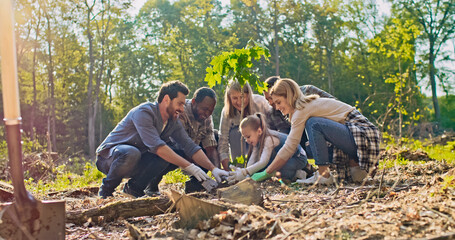 Enthusiastic multicultural group of volunteers of all ages planting trees having fun. Caring adults...