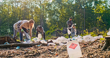 Group of enthusiastic people cleaning up forest picking up rubbish and putting it in garbage bags....