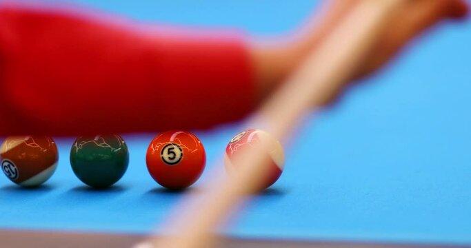 Hands of man hitting ball by cue during pool game training on blue table