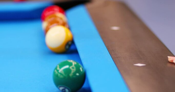 Hands of woman hitting ball by cue during pool training on blue table, close up