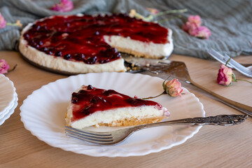 Cold cheesecake with cherry jelly served on wooden table with forks flowers roses and green veil