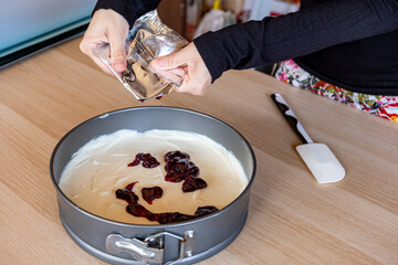 preparing cheesecake with red syrup of red berries and strawberries with cheesecake pan