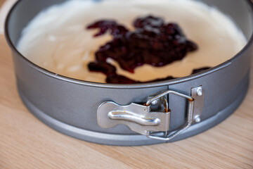 preparing cheesecake with red syrup of red berries and strawberries with cheesecake pan
