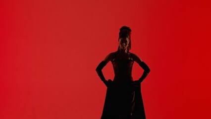 Woman dancer dancing on red background. Female in flamenco style dress performs elegant spanish dance moves with her hands and body in the studio.