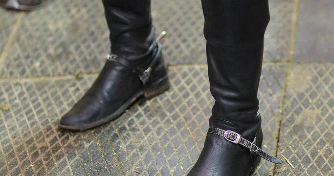 Legs in black leather boots with riding spurs, close up