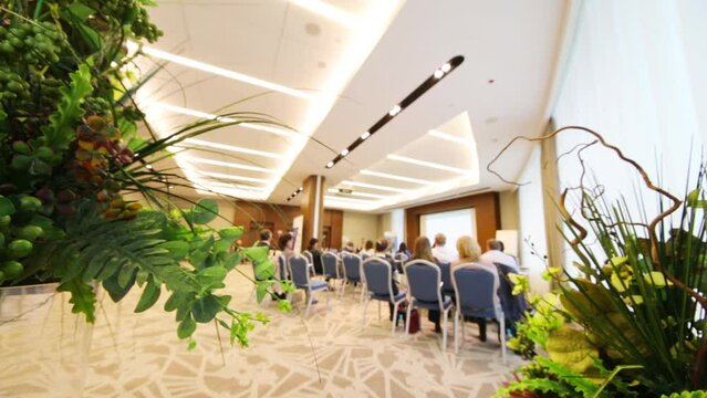 Audience during conference, focus on decorative plants