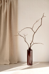 Vase with tree branch on table with natural sunlight shadow pattern, empty neutral white textured...