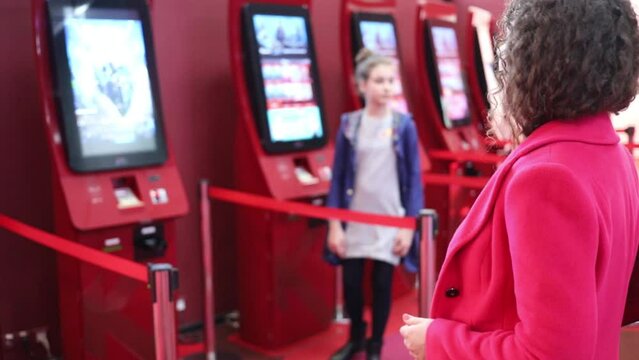  Woman and girl (two with MR) near machines for sale of tickets in Caro cinema (slow motion) 