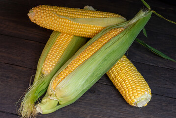 Close up view of raw corn cobs on wooden surface