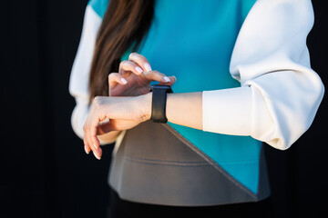 Woman uses a smart watch to measure the pulse on the hands. A woman does sports on the street. Fitness and a healthy lifestyle