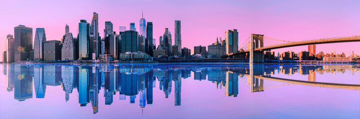 New York City Skyline, Tranquil Panoramic Sunrise Seascape over Manhattan skyscrapers and Brooklyn Bridge over the East River with calm water reflections