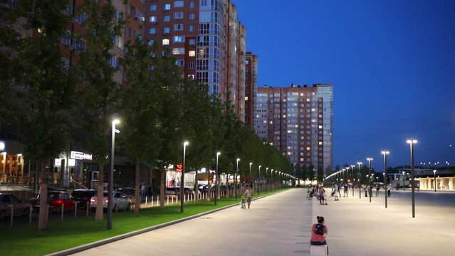 Residential buildings, alley with trees and lanterns at evening in Krasnodar, Russia